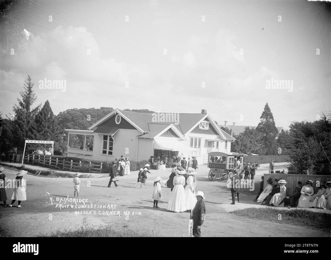 H Bainbridge fruit & Confectionery store, Takapuna, H Bainbridge fruit & Confectionery store, Takapuna, Auckland, Nouvelle-Zélande. Il y a un bus tiré par des chevaux avec 'Takapuna' à l'arrière chargé de gens. Photographie prise entre 1900 et 1930 Banque D'Images