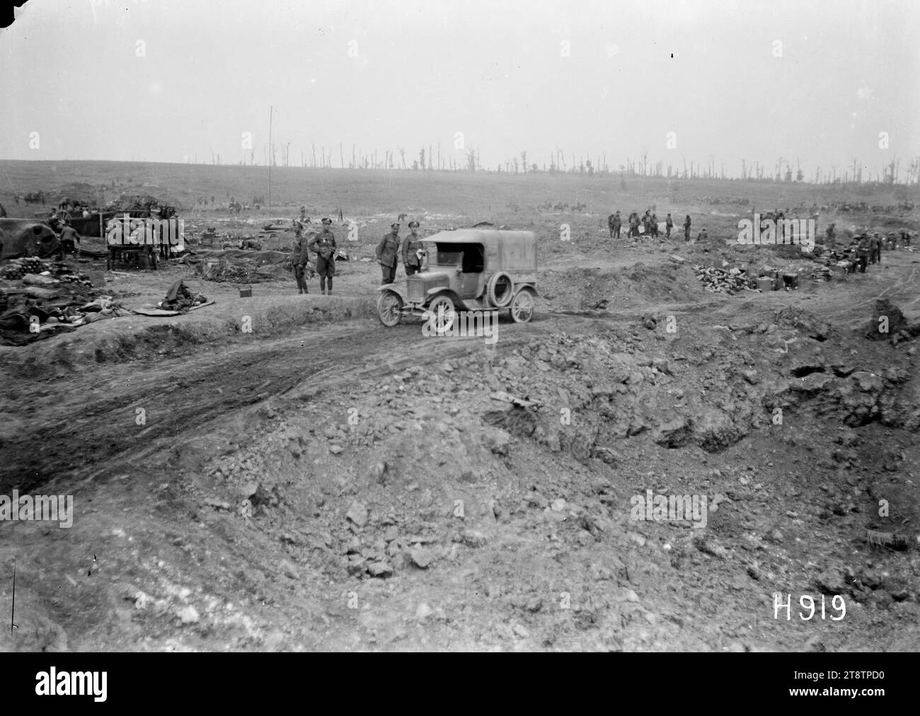 Une voiture à moteur passant un énorme trou de coquille dans un sol capturé, Grevillers, première Guerre mondiale, Une voiture à moteur voyageant le long d'un chemin de terre inégal passe un énorme trou de coquille dans un sol capturé pendant la première Guerre mondiale De petits groupes de soldats sont visibles en arrière-plan. Des souches d'arbres apparaissent à l'horizon. Photographie prise près de Grevillers, France, le 24 août 1918 Banque D'Images