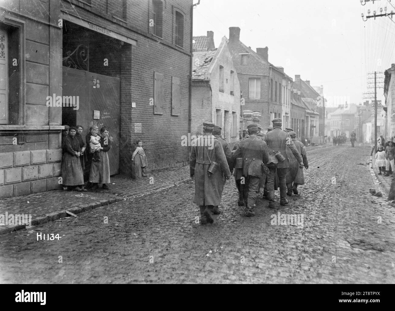 Prisonniers allemands de la première Guerre mondiale passant des habitants locaux, Solesmes, France, Un groupe de prisonniers de guerre allemands marchant dans une rue de la ville française de Solesmes vers la fin de la première Guerre mondiale Ils sont surveillés par un groupe d'habitants locaux, dont une femme tenant un bébé. Photographie prise le 1 novembre 1918 Banque D'Images