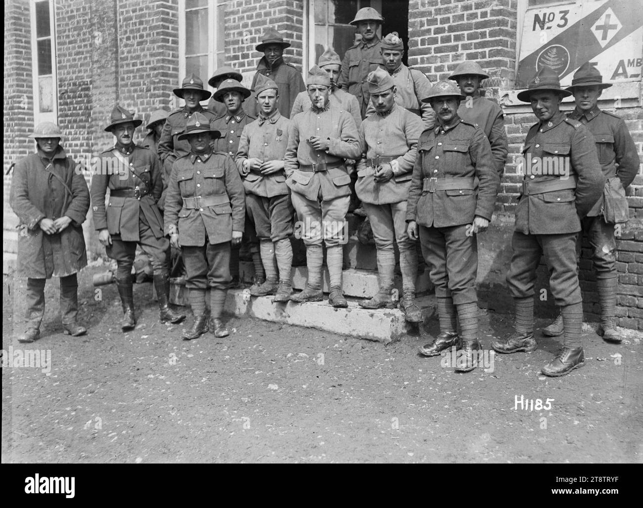 New Zealand and French Soldiers at the No. 3 New Zealand Field Ambulance, première Guerre mondiale, Un portrait de groupe de Néo-Zélandais et de soldats français à l'extérieur de l'Ambulance No. 3 New Zealand Field Ambulance en France pendant la première Guerre mondiale Sur la droite se trouve un panneau sur un mur avec une feuille de fougère et une croix rouge plus les lettres 'No. 3' et 'F. Amb.' Photographie prise à Louvencourt le 1 juin 1918 Banque D'Images