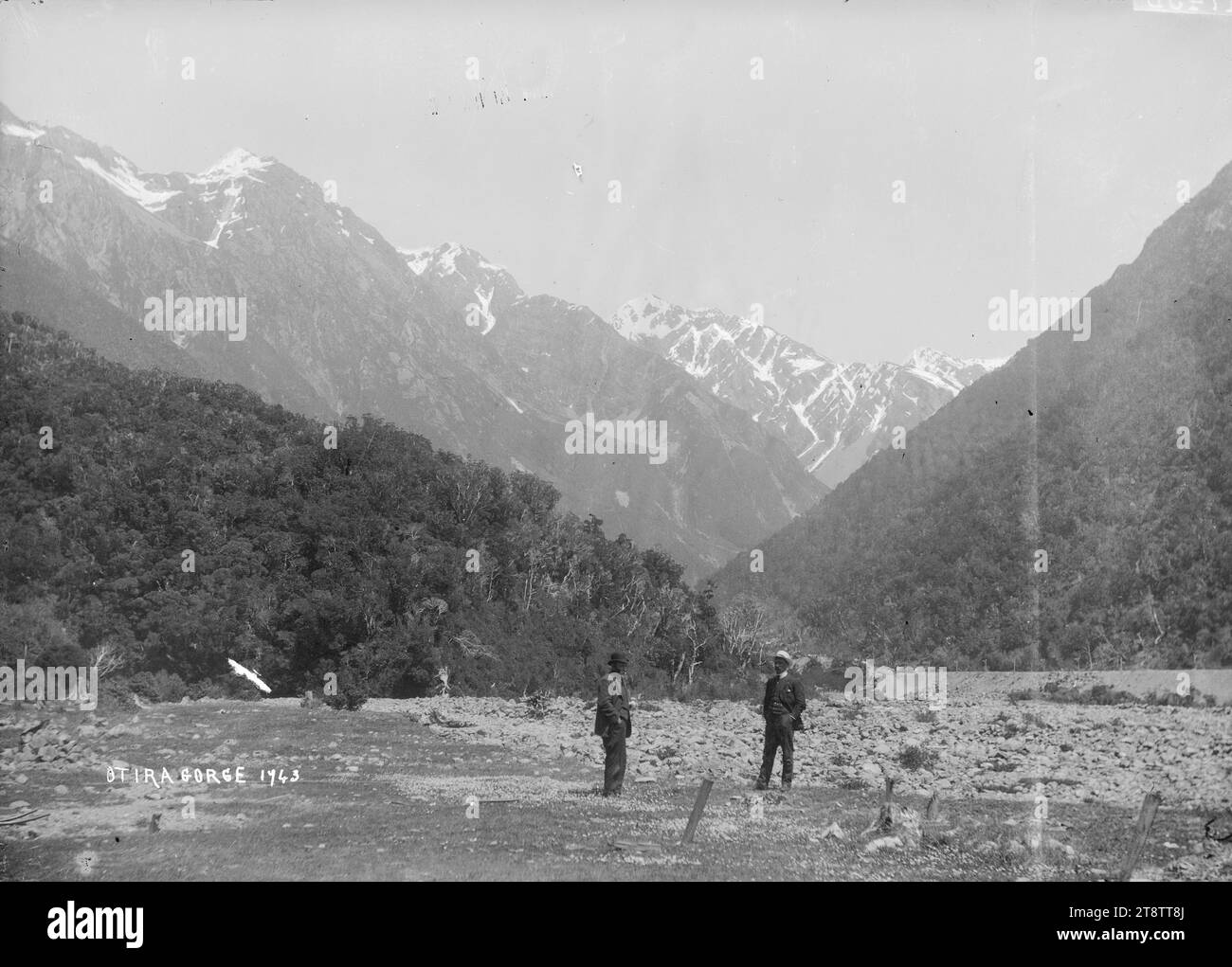 Les gorges d'Otira, deux hommes se tiennent au premier plan, avec une vue sur les montagnes enneigées au-dessus des gorges d'Otira Banque D'Images