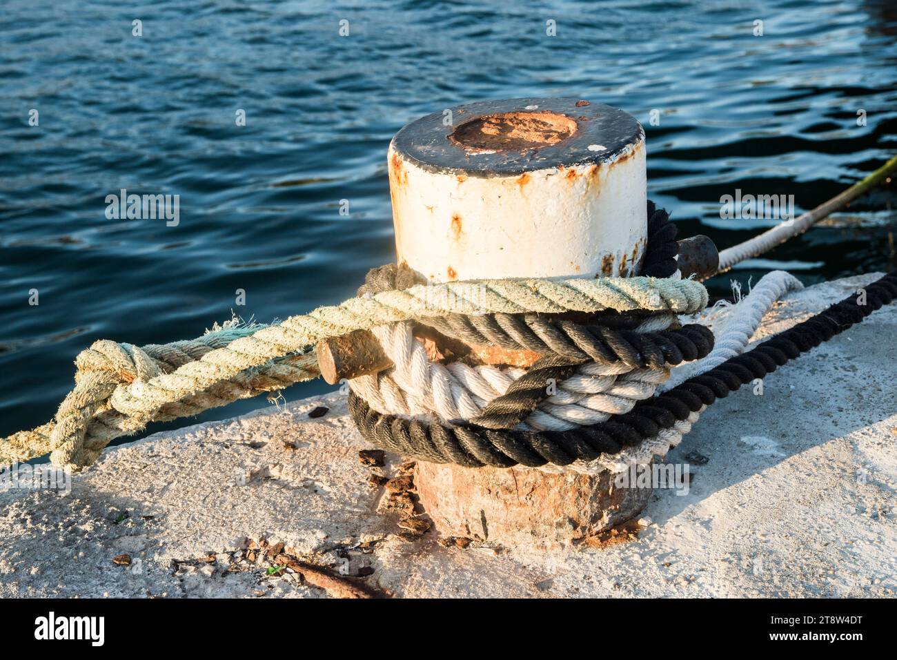 Vieux poteau d'amarrage de quai en métal avec corde pour sécuriser les bateaux de pêche à gros plan Banque D'Images