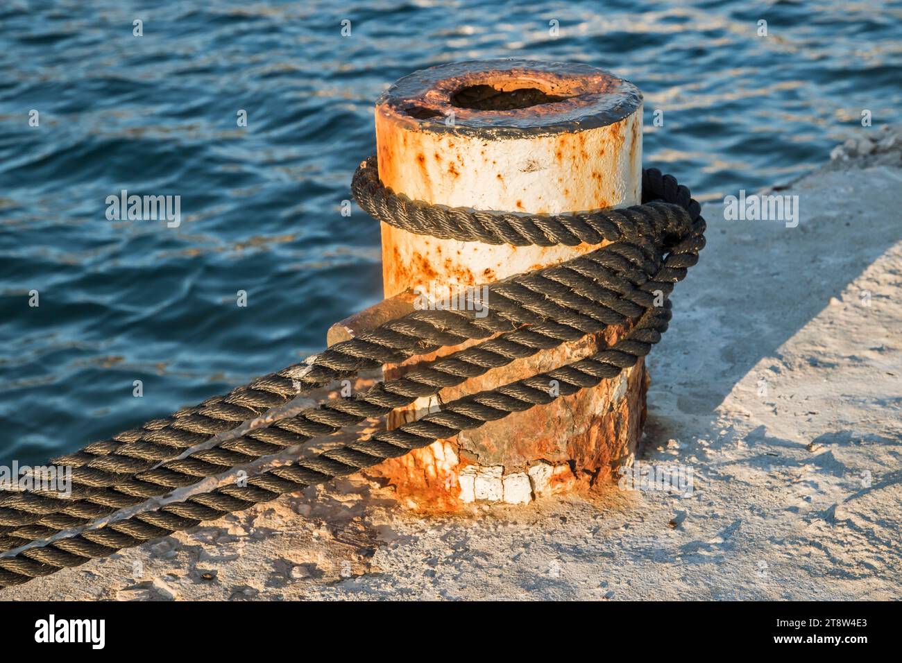 Vieux poteau d'amarrage de quai en métal avec corde pour sécuriser les bateaux de pêche à gros plan Banque D'Images