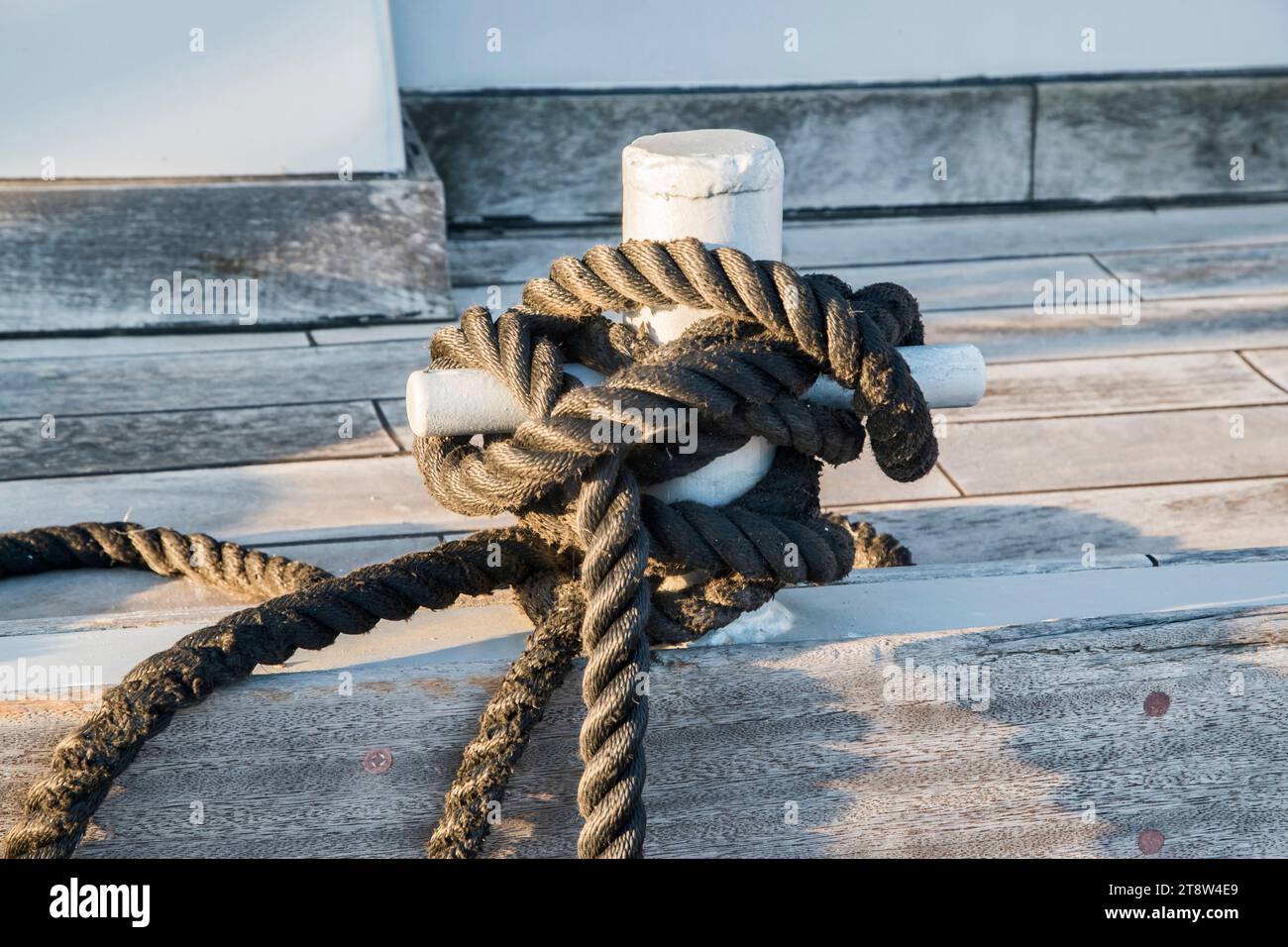 Vieux poteau d'amarrage de quai en métal avec corde pour sécuriser les bateaux de pêche à gros plan Banque D'Images