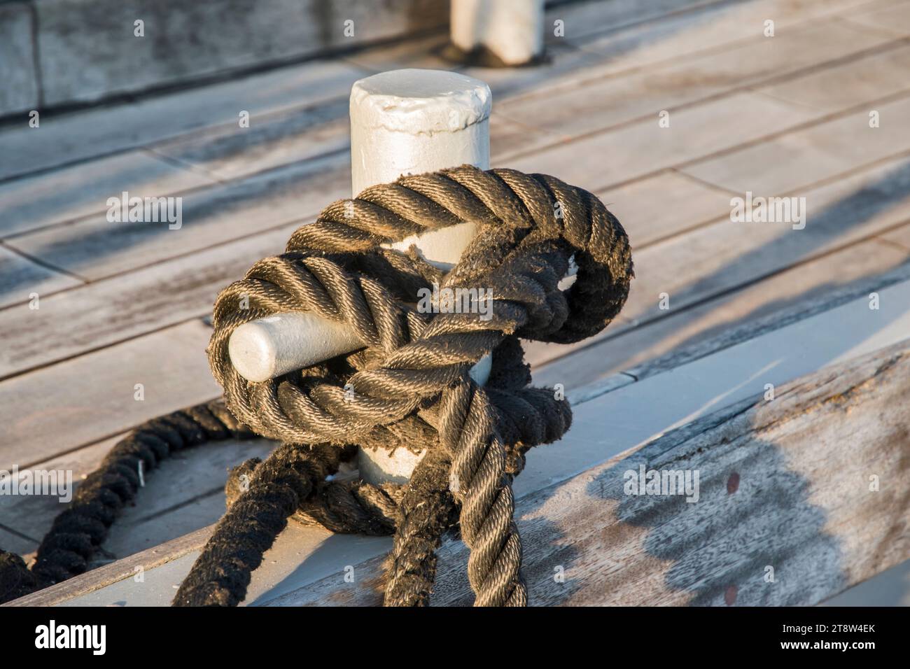 Vieux poteau d'amarrage de quai en métal avec corde pour sécuriser les bateaux de pêche à gros plan Banque D'Images