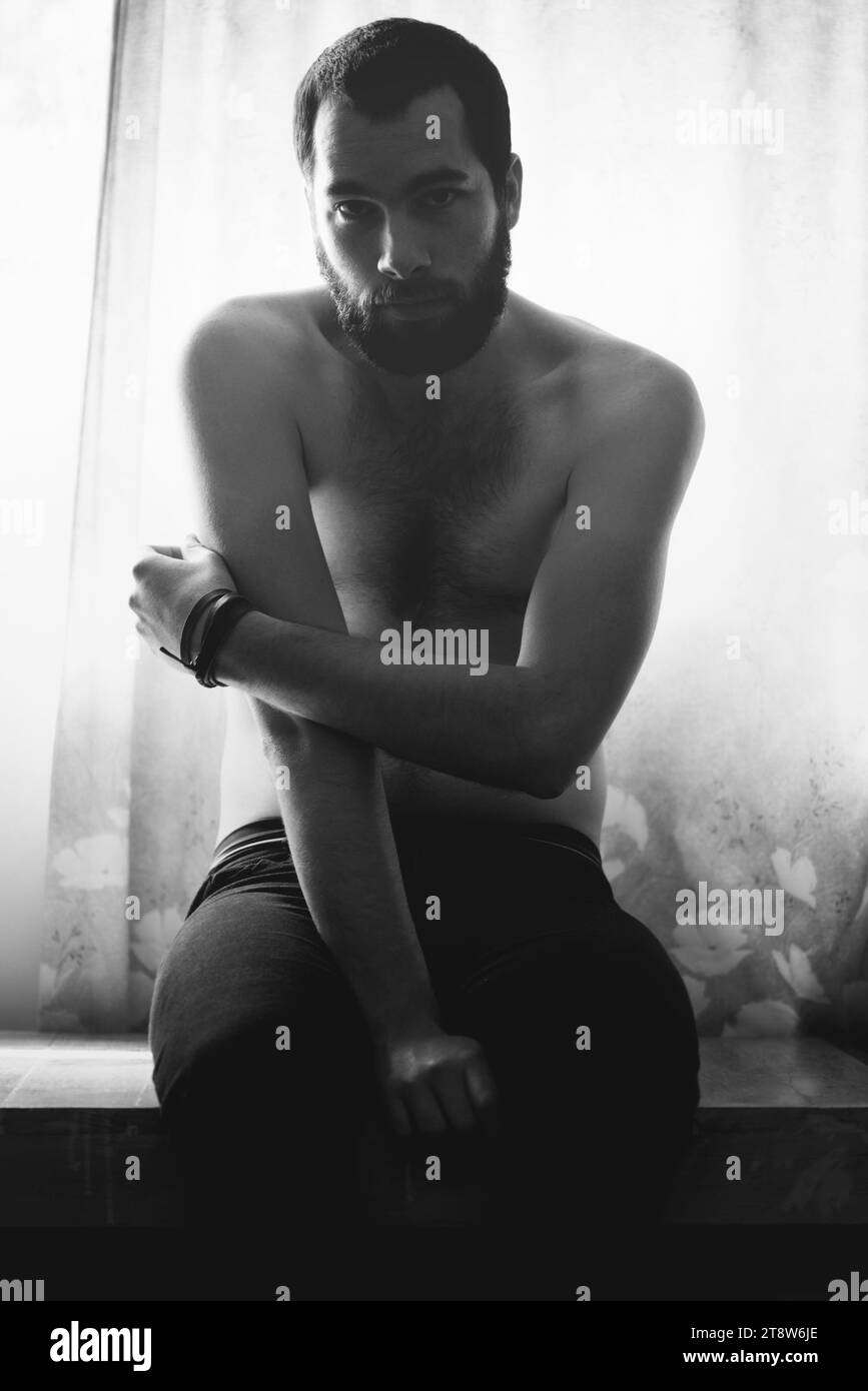 Homme, chambre et portrait avec pensée et créativité avec noir et blanc et barbe à la maison. Art, ombre et modèle masculin assis dans une maison avec un Banque D'Images