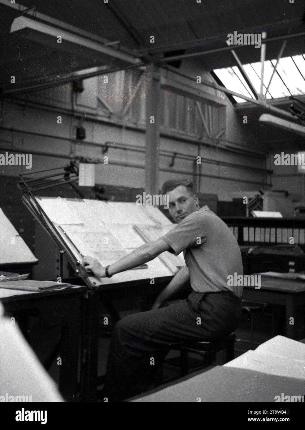 Années 1950, historique, dessinateur travaillant sur de grands drawings techniques à l'intérieur d'une unité industrielle légère, Angleterre, Royaume-Uni. Avant l'âge des ordinateurs, un dessinateur était un métier spécialisé impliquant la préparttion de dessins très détaillés concernant des machines ou des bâtiments. Banque D'Images