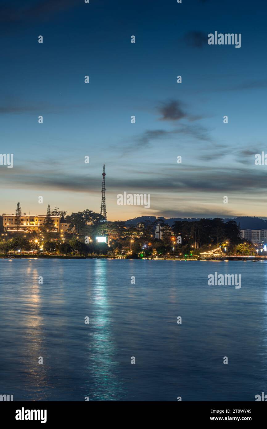 Vue sur le coucher du soleil sur le lac Xuan Huong, loin est Da Lat City avec des bâtiments de développement, transport, marché. Ville touristique avec place centrale de Da Lat Banque D'Images