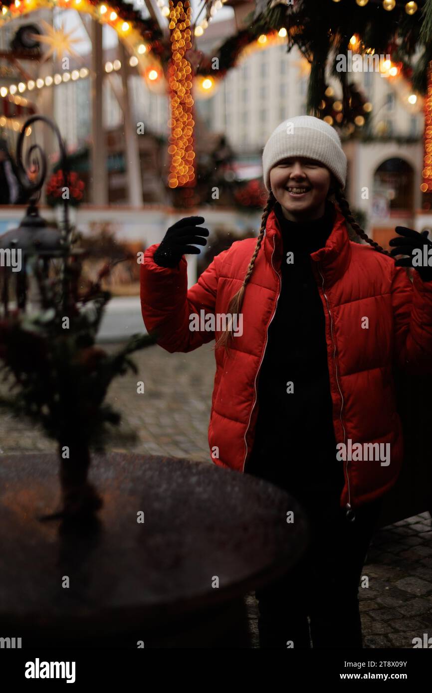 Une jeune femme dans une veste rouge et un chapeau blanc sur le fond du marché de Noël à Dresde, en Allemagne Banque D'Images