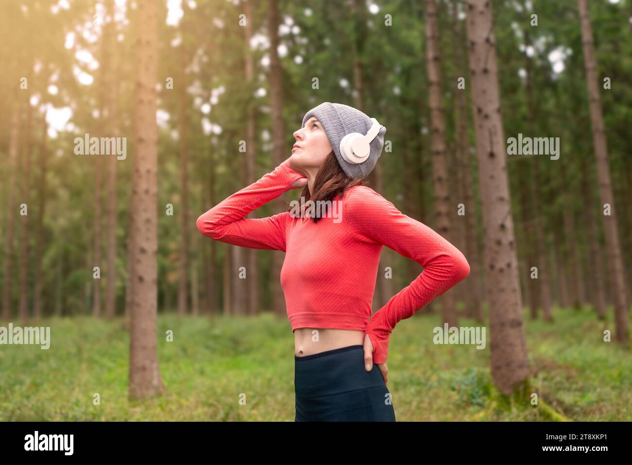 Sportive femme coureuse s'entraînant à l'extérieur dans une forêt, écoutant de la musique avec des écouteurs Banque D'Images