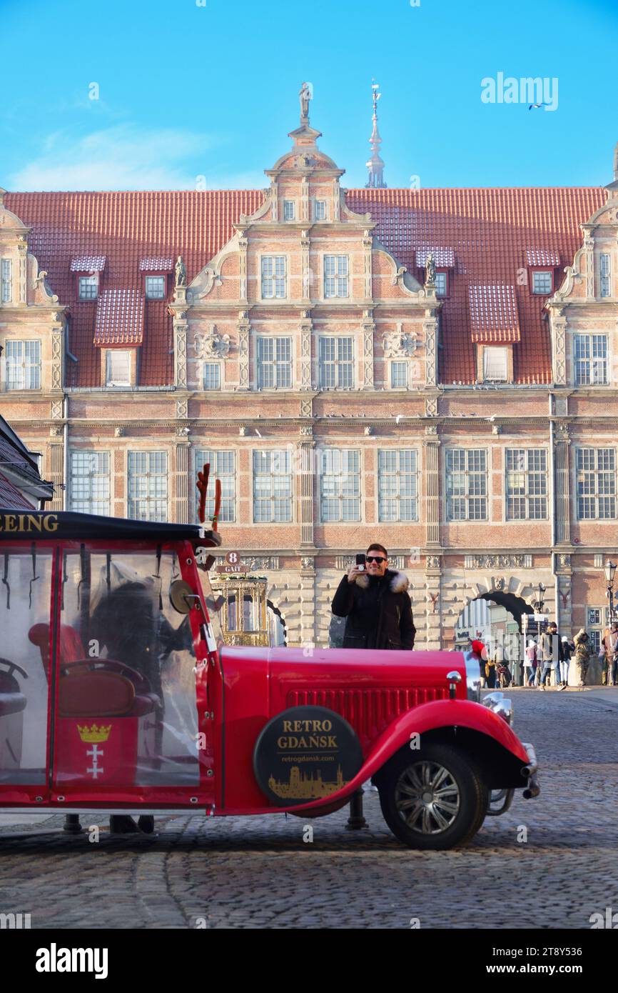 Gdansk, Pologne 15 décembre 2022 : voiture rétro rouge vintage avec touriste. Porte verte à Gdansk, Pologne Banque D'Images