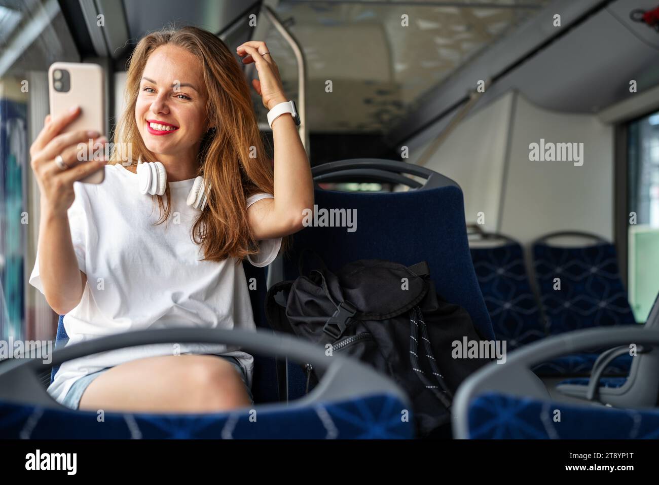 Femme urbaine utiliser son téléphone comme un miroir tout en voyageant en bus. Banque D'Images