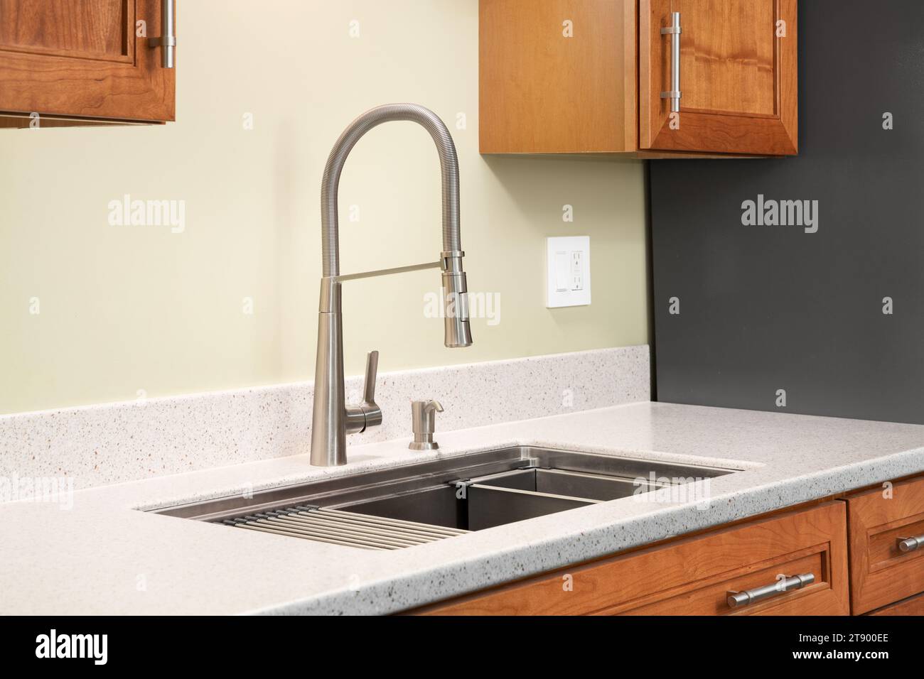 Un détail de robinet de cuisine avec un comptoir en quartz, des armoires en bois et un robinet à poignée unique en acier inoxydable. Banque D'Images