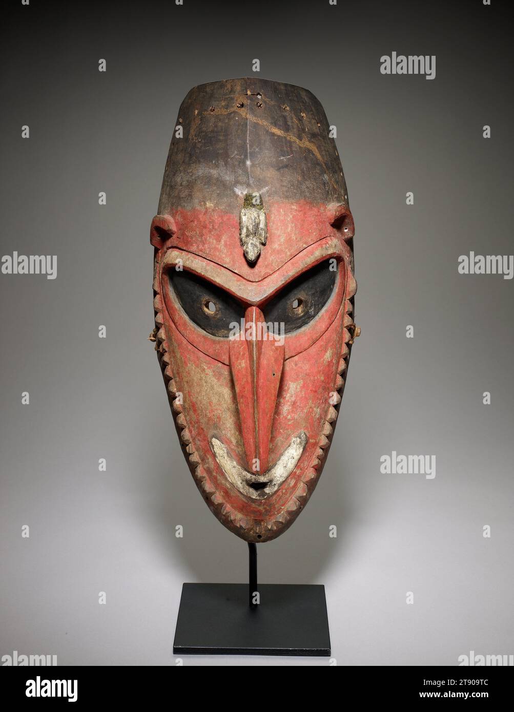 Masque, 1920s-1930s, 20 3/4 x 9 9/16 x 6 7/8 pouces (52,71 x 24,29 x 17,46 cm), Bois, pigments, fibres végétales, Papouasie-Nouvelle-Guinée, 20e siècle, ce masque, avec ses yeux profonds et son nez fort et croqué, est l'incarnation d'un esprit ancêtre de l'île de Manam, située à l'embouchure de la rivière Ramu, juste au large de la côte nord de la Nouvelle-Guinée. Il était autrefois orné de bijoux en coquille dans ses oreilles et nez percés, démontrant le respect pour l'ancêtre. Porté dans le cadre d’un costume de fibre plus grand, le masque était tenu devant le visage avec une baguette de morsure, toujours présente sur cet exemple Banque D'Images