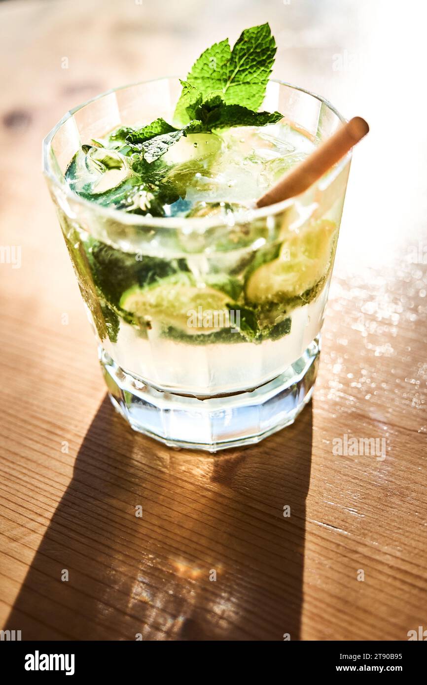 Verre Mojito avec paille sur table en bois et lumière d'été Banque D'Images