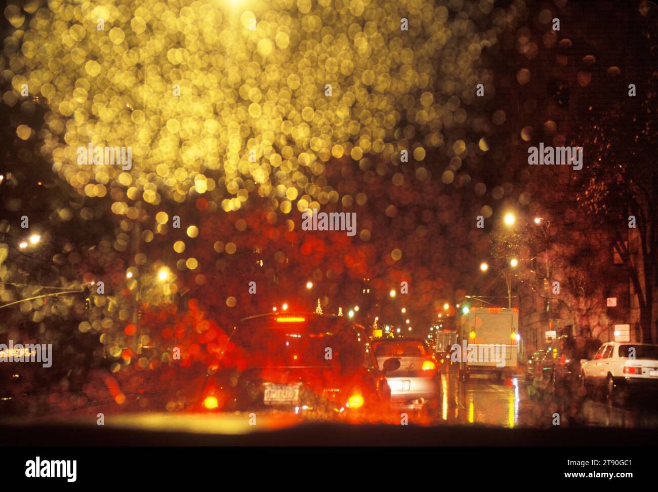 Conduite sous la pluie la nuit. Réflexion des feux arrière et gouttes de pluie sur le pare-brise ou le pare-brise de l'habitacle d'une voiture. Voyage dans Midtown Manhattan NYC Banque D'Images