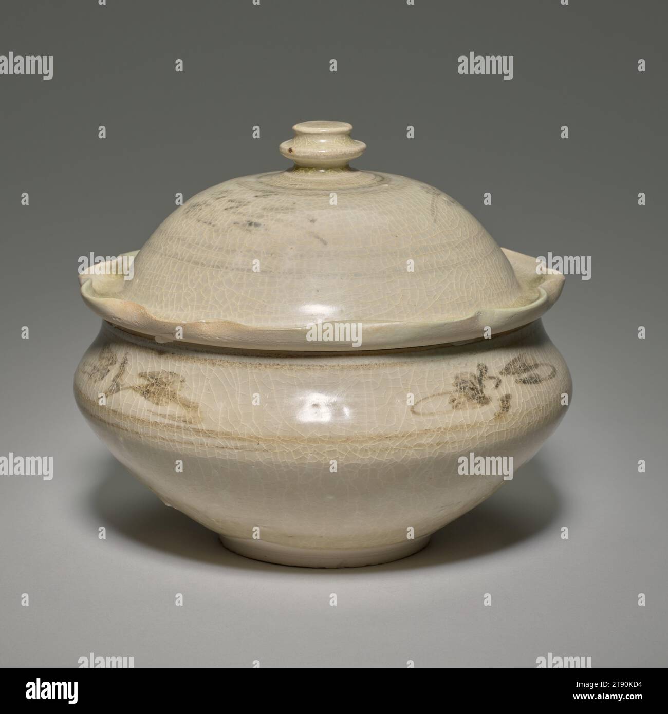 Bol avec couvercle, dynastie le ou Tran, 13e-14e siècle, 6 x 7 po. (15,2 x 17,78 cm), grès émaillé, Vietnam, dynastie le ou Tran, 13e-14e siècle, bien qu’influencés par les modèles chinois, les potiers vietnamiens ont fait leurs propres innovations et ont ajouté de nouveaux éléments à leurs créations. Le couvercle bombé de ce bol, par exemple, a un rebord festonné qui imite probablement le bord d'une feuille de lotus. Le décor floral sous-glacé spontanément brossé est exécuté avec un composé riche en fer. Ce type de bol couvert était populaire aux 13e et 14e siècles Banque D'Images