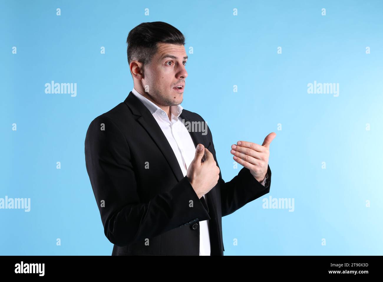 Homme émotionnel en costume pointant vers lui-même sur fond bleu clair Banque D'Images