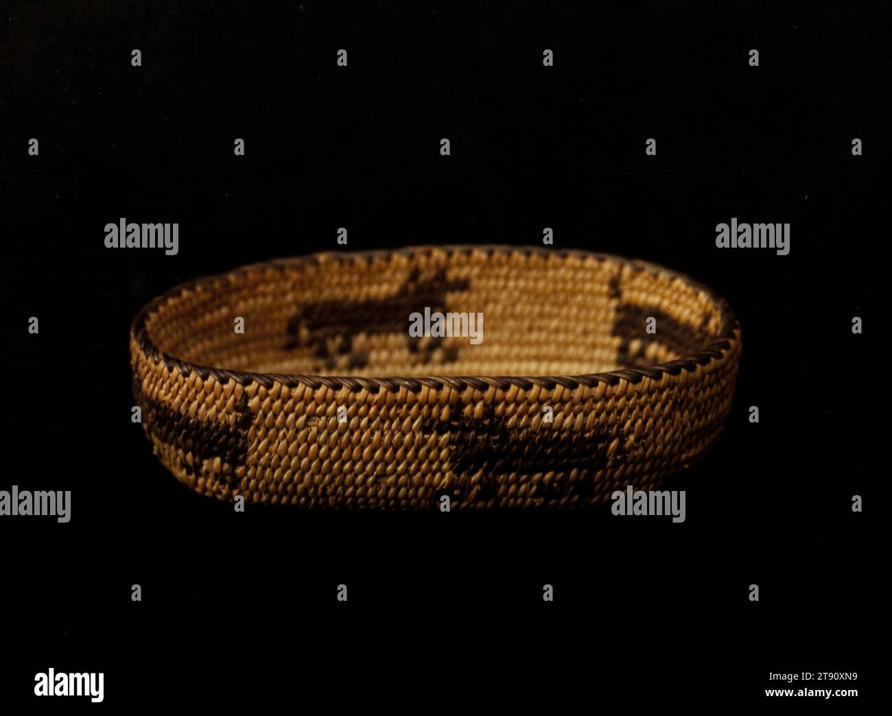 Panier, 20e siècle, 3/4 x 1 3/8 x 2 5/8 po. (1,91 x 3,49 x 6,67 cm), Grass Fibers, États-Unis, 20e siècle, l’offre et la demande du marché qui se sont développées entre les touristes euro-américains et les corniers Akimel O’othom et Tohono O’odham démontrent le haut niveau d’ingéniosité et de productivité des tribus. Les articles de nouveauté inventés par les artistes autochtones comprennent des paniers de papier usagé, des effigies animales et humaines, et des miniatures de formes populaires de paniers. Le plus petit panier ici mesure seulement un demi pouce de diamètre. Banque D'Images