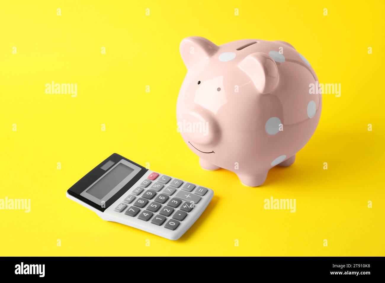 Calculatrice et tirelire rose sur fond jaune Banque D'Images