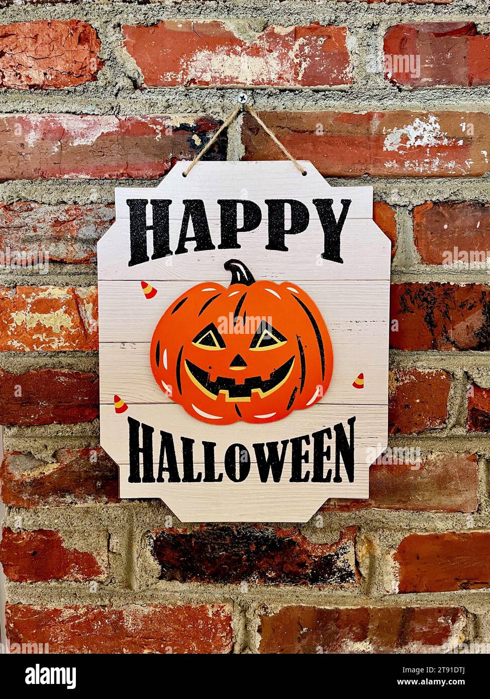 Un signe «Happy Halloween» avec une citrouille souriante accroche sur le mur d'une maison. Banque D'Images