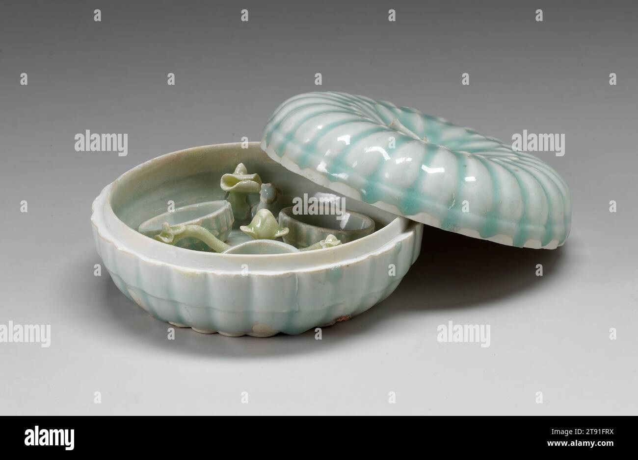 Boîte à cosmétiques Melon Form, 12e-13e siècle, atelier de la famille Tuan, chinois, 2 1/2 x 5 3/8 x 5 3/8 po. (6,35 x 13,65 x 13,65 cm) (total), porcelaine Qingbai avec glaçage bleu pâle, Chine, 12e-13e siècle, en forme de melon aplati, cette boîte à couvercle est placée à l'intérieur avec un grand bourgeon floral central à partir duquel sortent trois branches chacune avec des feuilles et des bourgeons à fourrure entrecoupés de trois petits récipients arrondis vraisemblablement pour les cosmétiques. De telles boîtes, ainsi que des boîtes à encre scellée et à couvercle multifonctionnel, ont été produites en grande quantité dans les fours Yingqing Banque D'Images