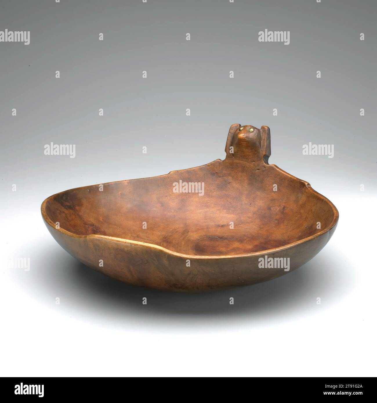 Bol, c. 1750-1850, 6 1/4 x 15 7/8 x 14 15/16 po. (15,88 x 40,32 x 37,94 cm), ronce d'érable, punaises en laiton, États-Unis, 19th Century, les bols en bois faisaient partie intégrante de la vie traditionnelle des groupes tribaux des régions des Plaines et des Grands Lacs/Woodlands. Sculptés par les hommes, ils étaient principalement utilisés à des fins utilitaires et cérémonielles ; les exemples décorés étaient très appréciés. La tête sur ce bol représente probablement Eyah, l'esprit de «manger chaleureusement». Sculpter une image d'Eyah sur un bol a renforcé la coutume de consommer de grandes quantités de nourriture offerte Banque D'Images