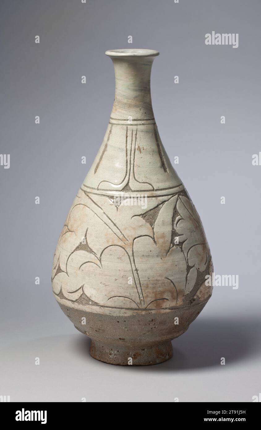 Bouteille avec feuilles de pivoine, seconde moitié du 15e siècle, coréen inconnu, 12 11/16 × 6 3/4 × 6 3/4 po. (32,23 × 17,15 × 17,15 cm), Buncheong ware ; faïence avec sous-glaçure à motif sgraffite, Corée, 15e siècle, cette bouteille Buncheong est un exemple de motif sgraffite. Les potiers ont d'abord brossé la surface avec de la barbotine blanche (argile liquide) ; après qu'elle ait séché jusqu'à obtenir une dureté semblable au cuir, ils ont incisé le dessin avec des lignes fines, et certaines zones ont été sculptées. De cette manière, le motif décoratif en blanc - dans ce cas un dessin de feuille de pivoine défilant - se distingue dramatiquement par rapport à l'argile plus foncée. Banque D'Images