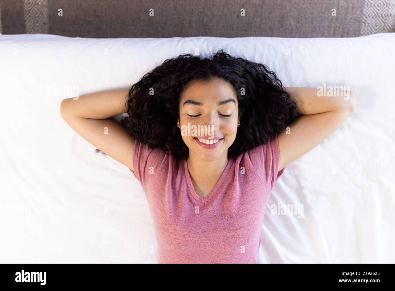 Vue aérienne de la femme biracial heureuse couchée dans le lit à la maison ensoleillée Banque D'Images
