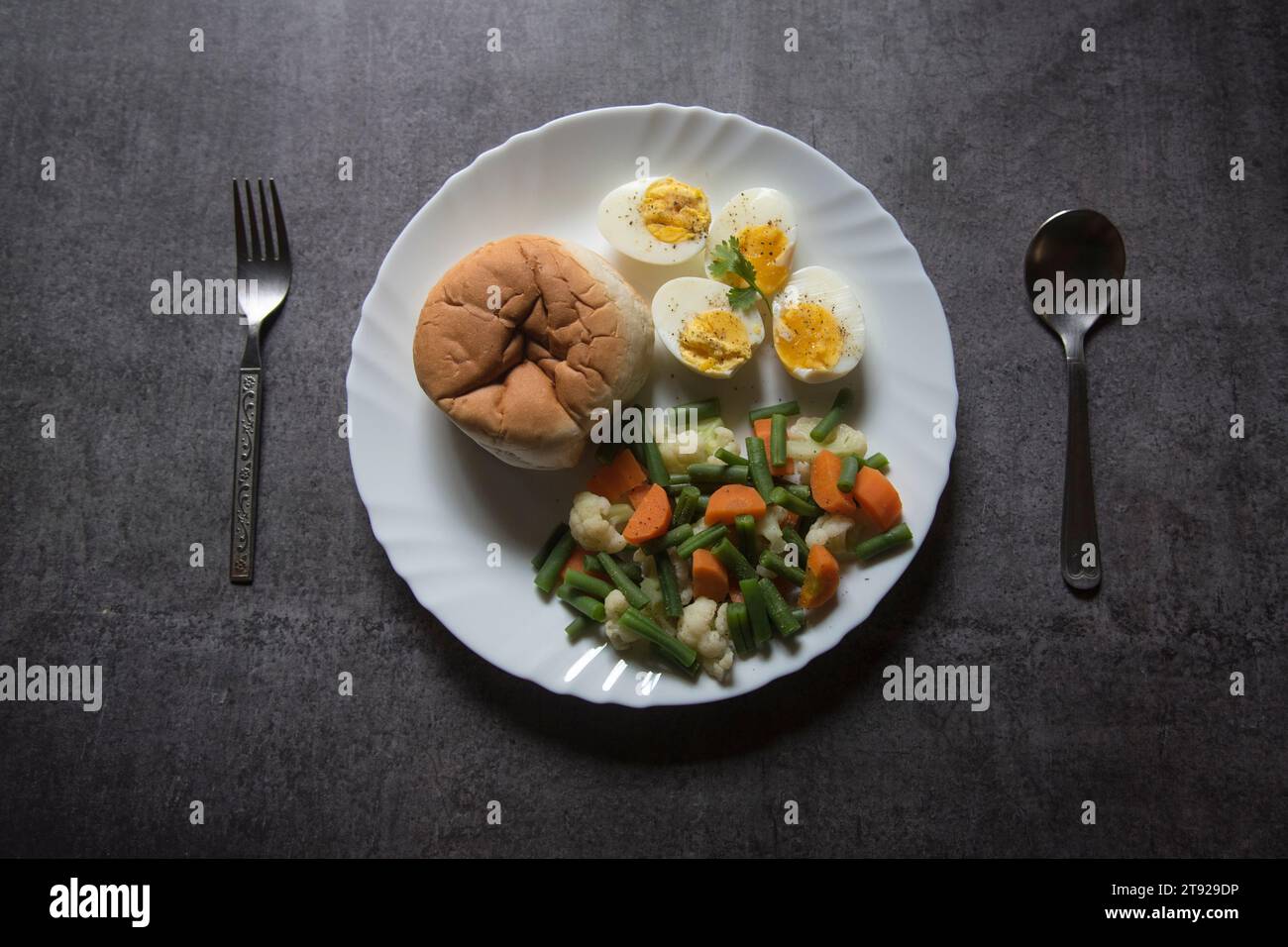 Vue d'en haut de la nourriture saine de petit déjeuner pain, oeufs et légumes bouillis sur une assiette. Banque D'Images