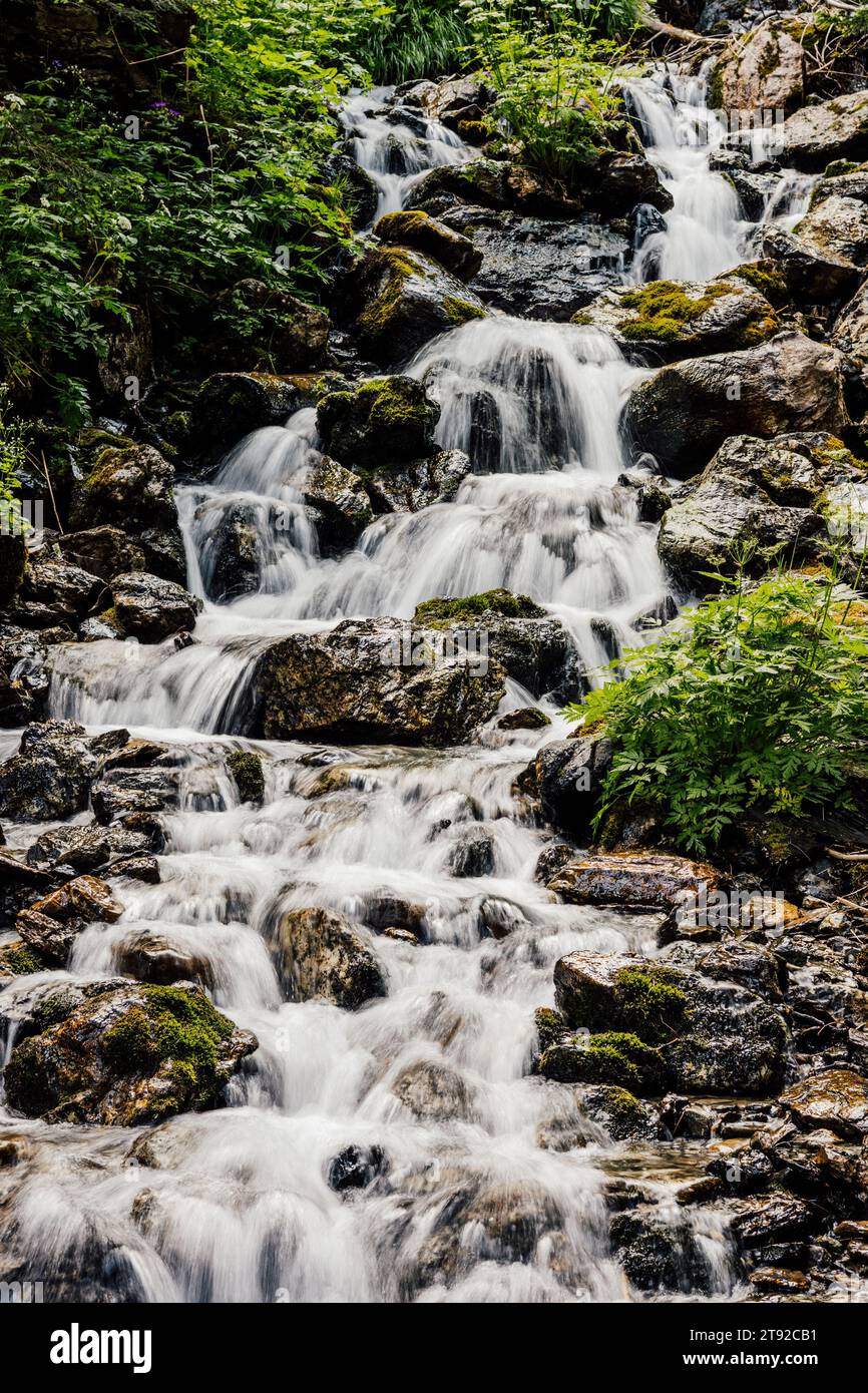 Une longue exposition d'une chute d'eau tombant en cascade au milieu des affleurements rocheux et de la végétation luxuriante Banque D'Images