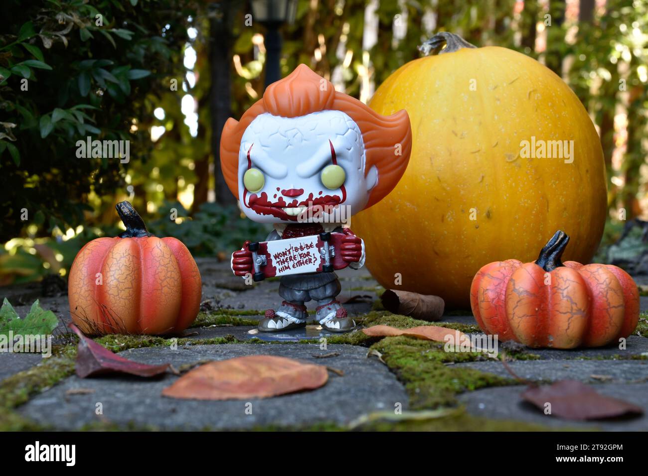 Funko Pop figurine d'action de Pennywise mal clown avec planche à roulettes sanglante du film d'horreur IT. Halloween, saison effrayante, citrouilles, mousse, feuilles d'automne. Banque D'Images