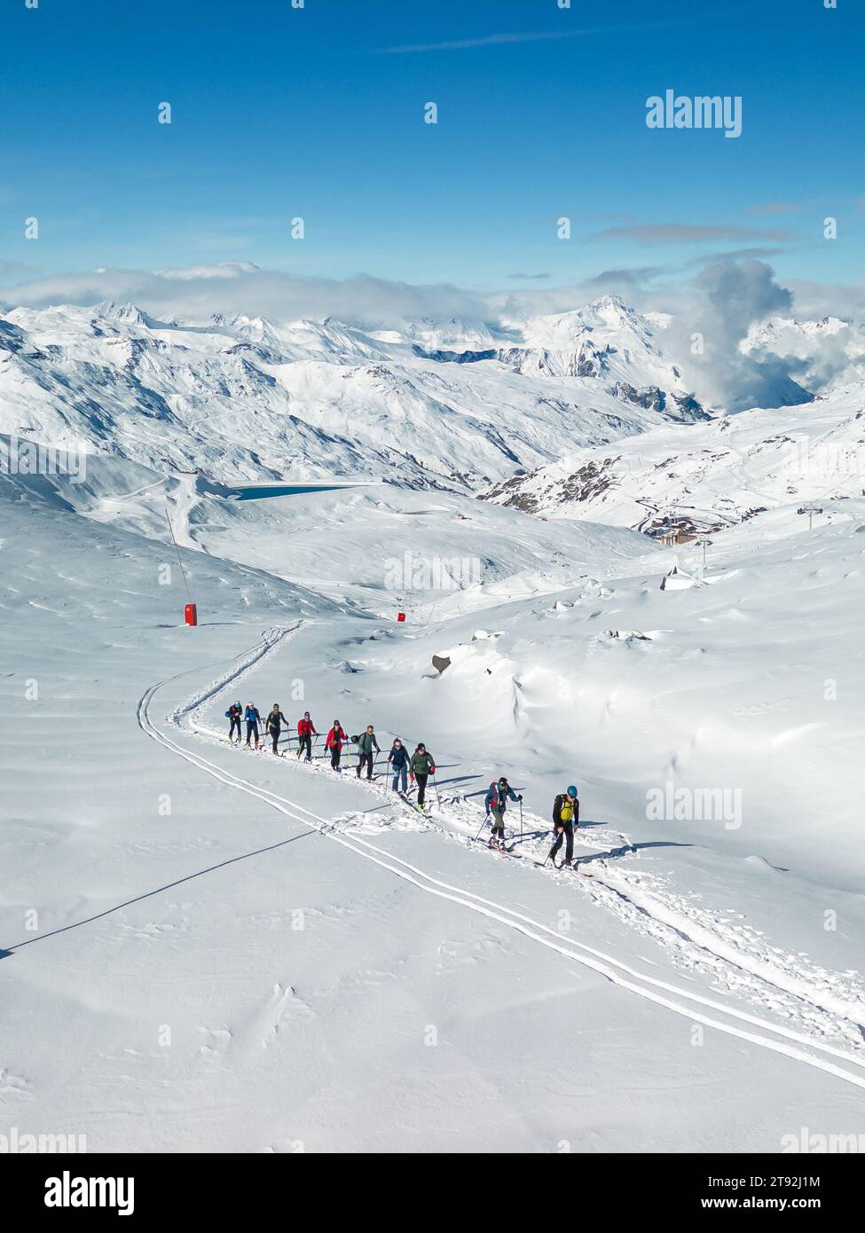 Un drone capture les touristes skiant à Val Thorens au milieu de paysages enneigés, encadrés par un ciel bleu éclatant. Banque D'Images