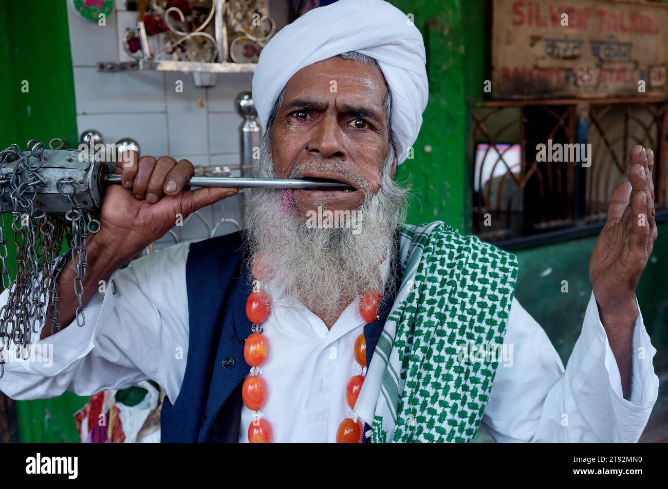 Un fakir, un ascète musulman errant exécutant des exploits étranges et des tours magiques, menaçant de lui percer la joue avec un parler acéré ; Mumbai, Inde Banque D'Images