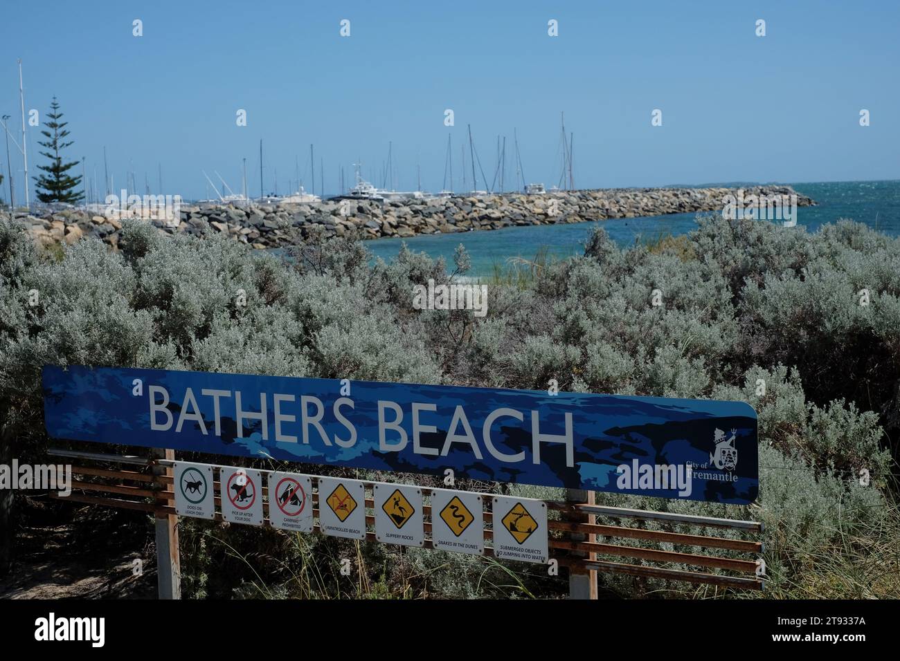 Bathers Beach signe avec des arbustes côtiers, des avertissements, des serpents - digue et marina en arrière-plan de ce paysage côtier australien Banque D'Images