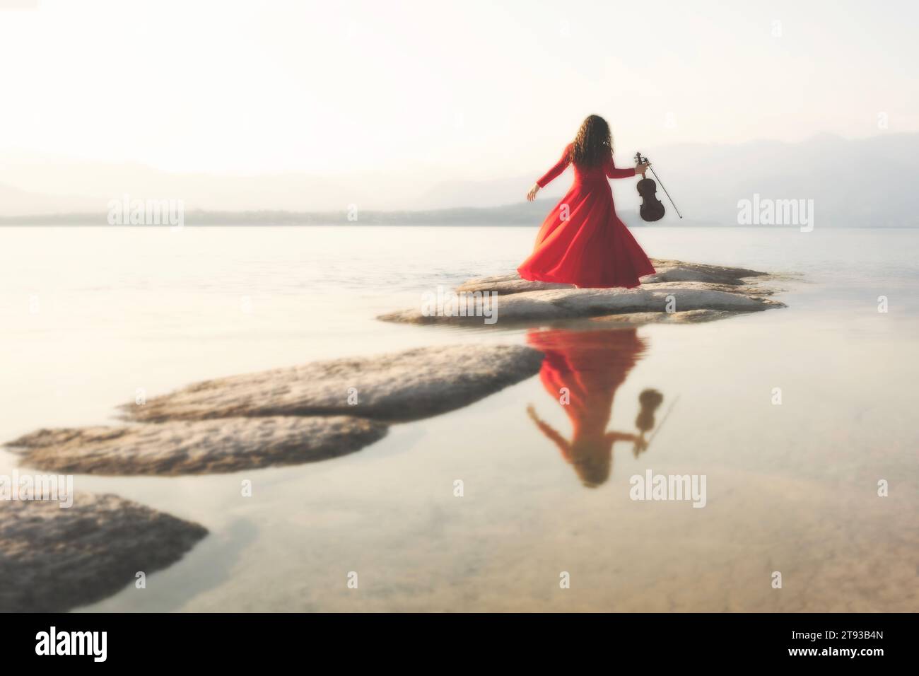 femme en rouge au violon saute entre un chemin de pierres menant à la mer, concept abstrait Banque D'Images