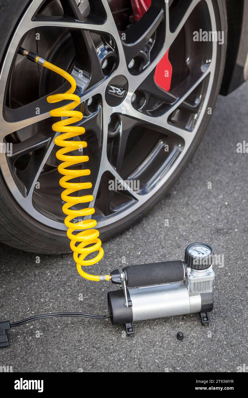 Compresseur d'air de voiture compact de 12 V en position de travail, gonflant les roues, avec contrôle de la pression des pneus d'automobile à l'extérieur Banque D'Images