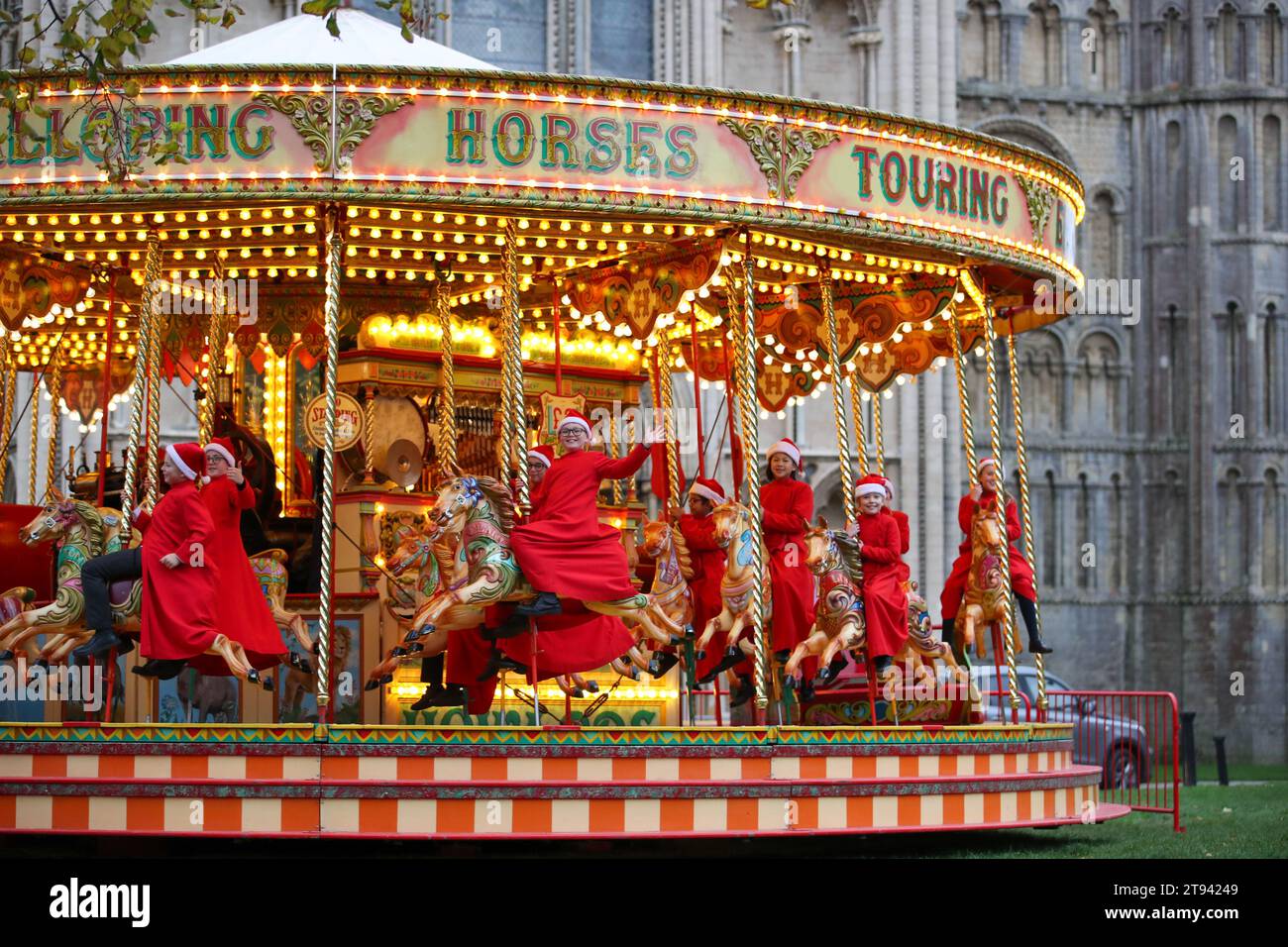 Des choristes de la cathédrale d'Ely vont faire un tour sur le carrousel traditionnel au marché de Noël de la ville après la pratique de chœur tôt le matin. Banque D'Images