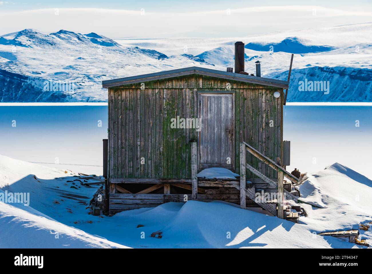 Une cabane en bois dans un paysage montagneux enneigé au Groenland. Banque D'Images