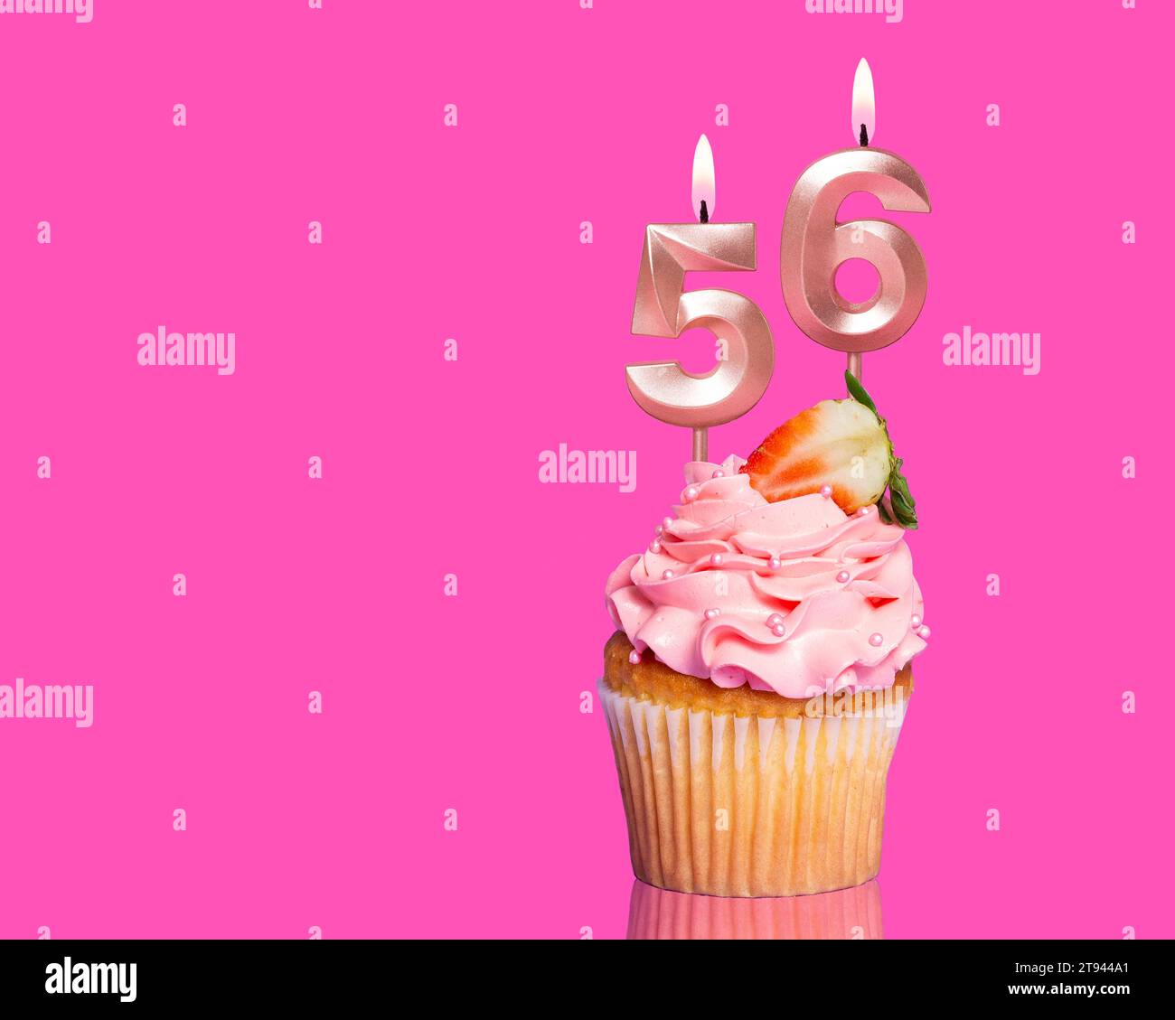 Cupcake d'anniversaire avec bougie numéro 56 - sur fond rose chaud. Banque D'Images