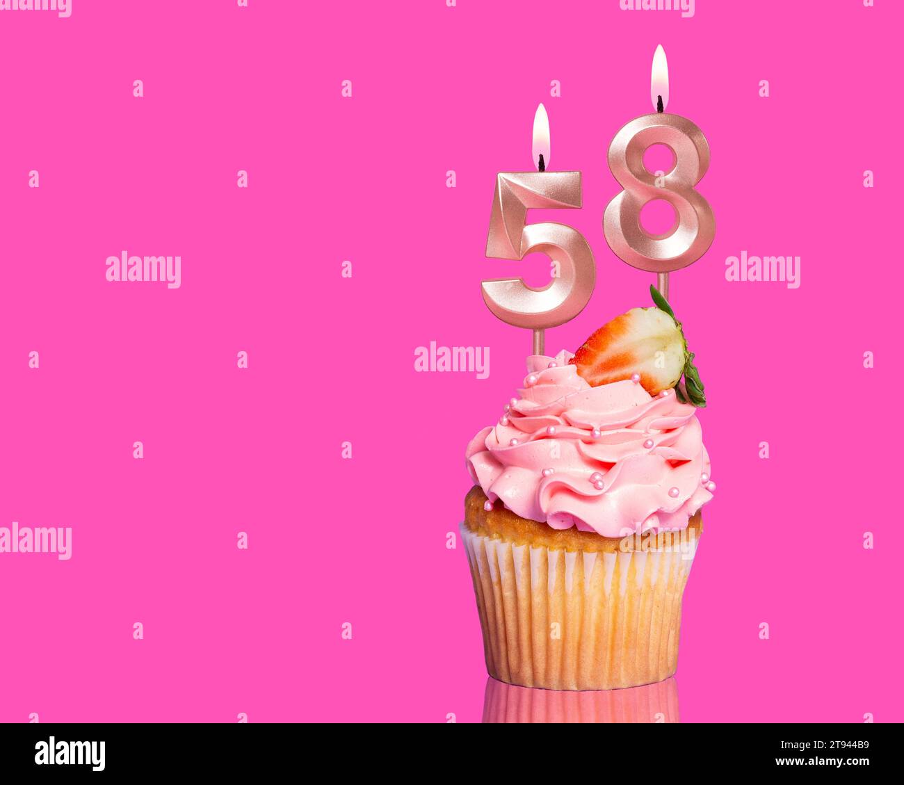 Cupcake d'anniversaire avec bougie numéro 58 - sur fond rose chaud. Banque D'Images