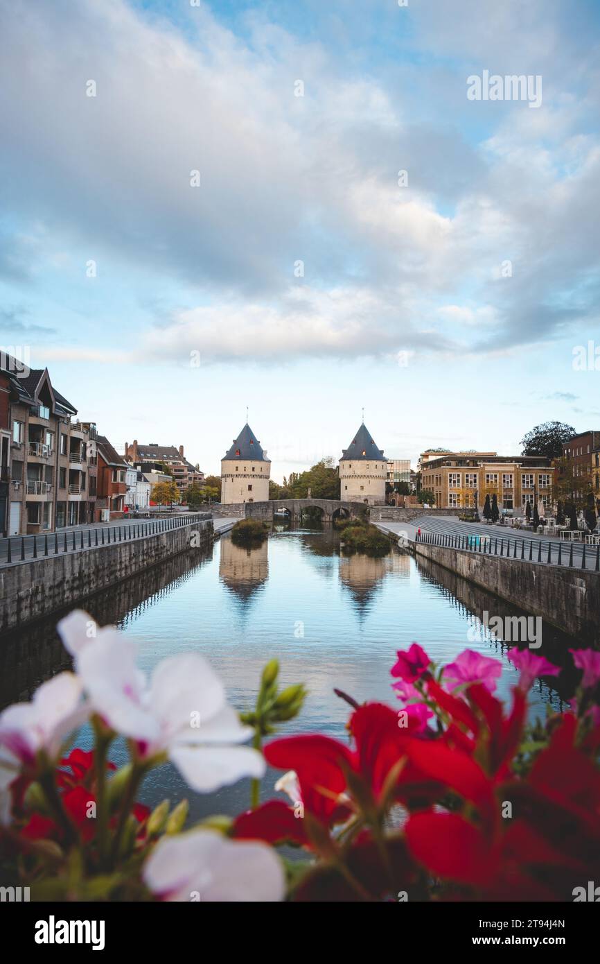 Centre-ville de Kortrijk avec deux tours historiques au bord de la rivière. Fleurs, rivière et bâtiments historiques. Ville belge dans le sud du pays. Banque D'Images