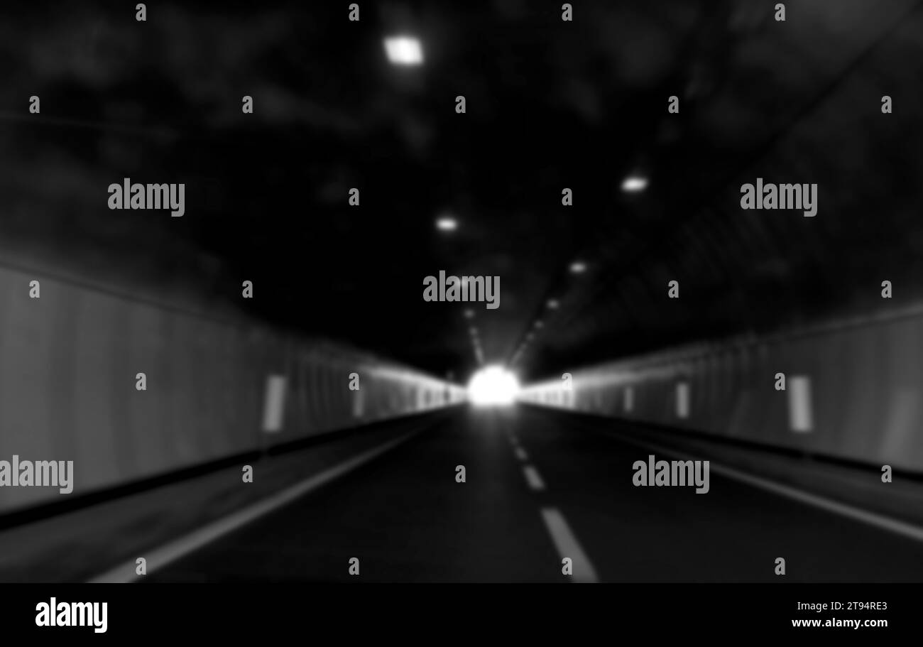 tunnel routier volontairement flouté sans voitures et vous voyez la lumière au loin en noir et blanc Banque D'Images