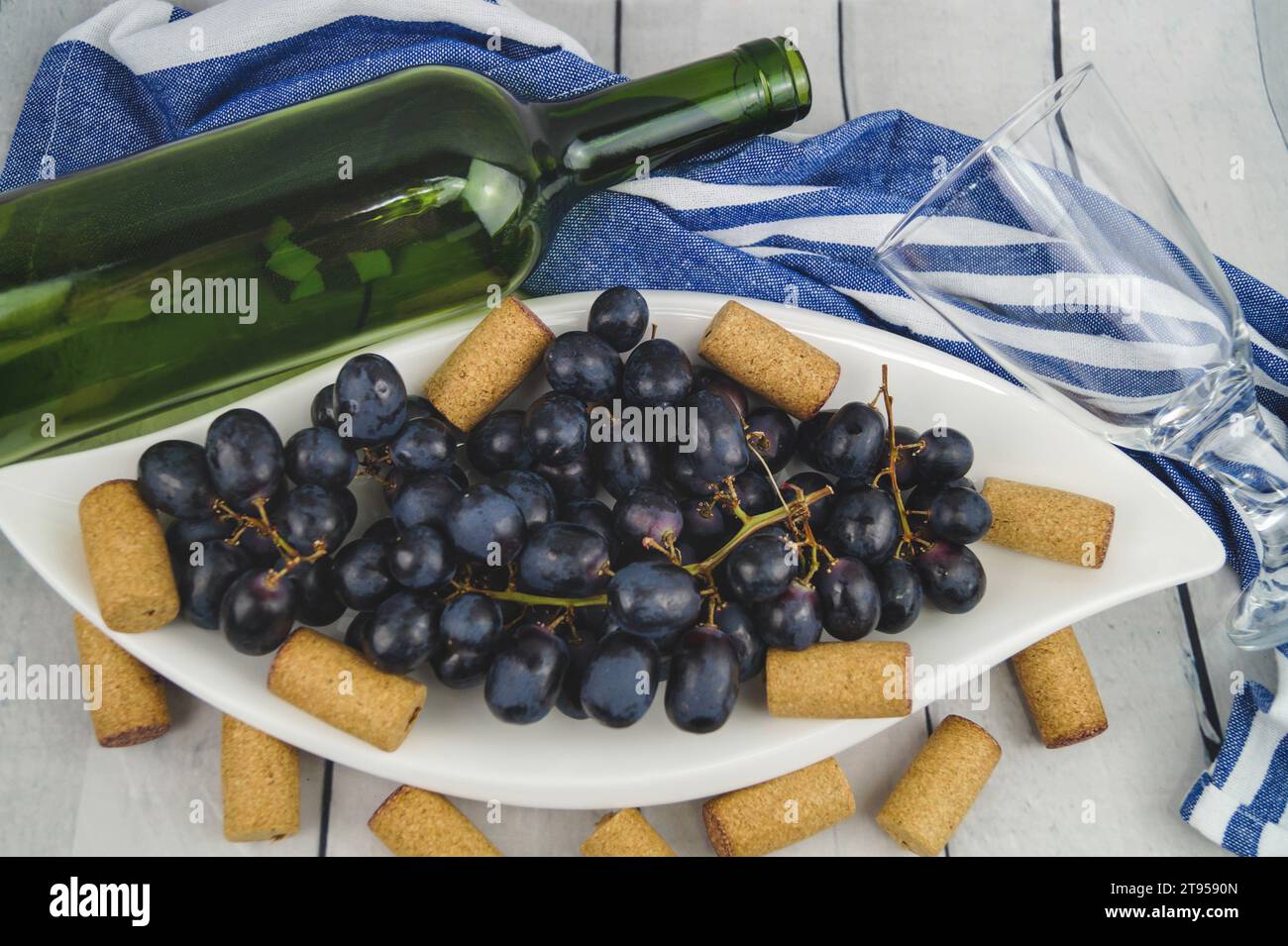 raisins noirs sur assiette, bouchons et bouteille Banque D'Images