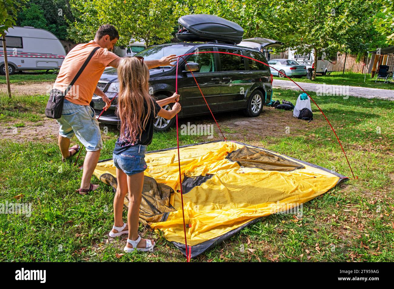 Papa et les enfants ont installé une tente dans un camp de camping. Vacances en famille et voyages en voiture Banque D'Images