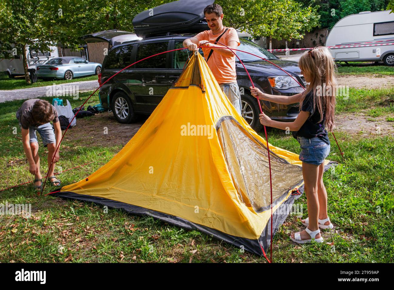 Papa et les enfants ont installé une tente dans un camp de camping. Vacances en famille et voyages en voiture Banque D'Images