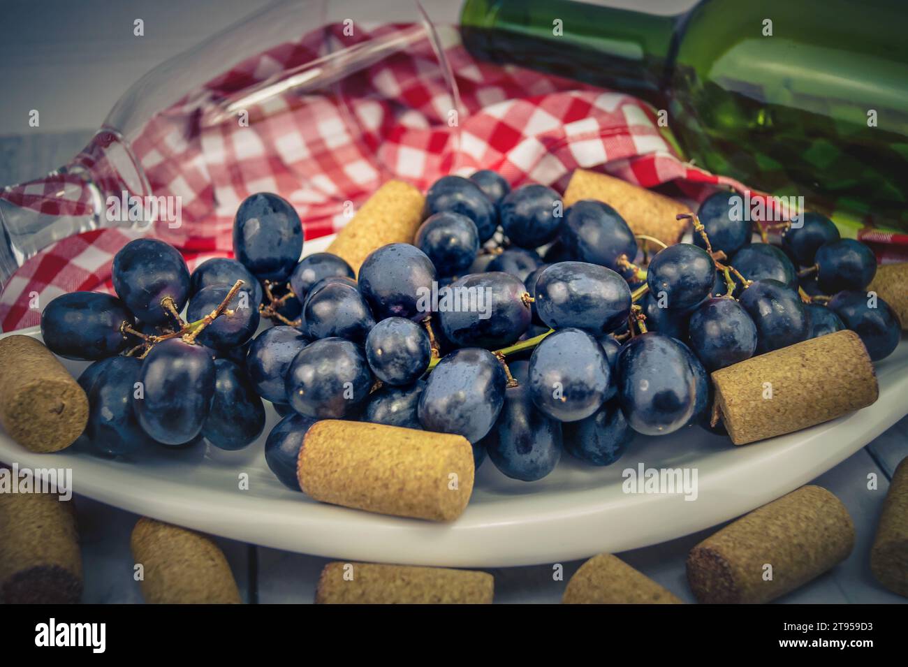raisins noirs sur assiette, bouchons, verre et bouteille Banque D'Images