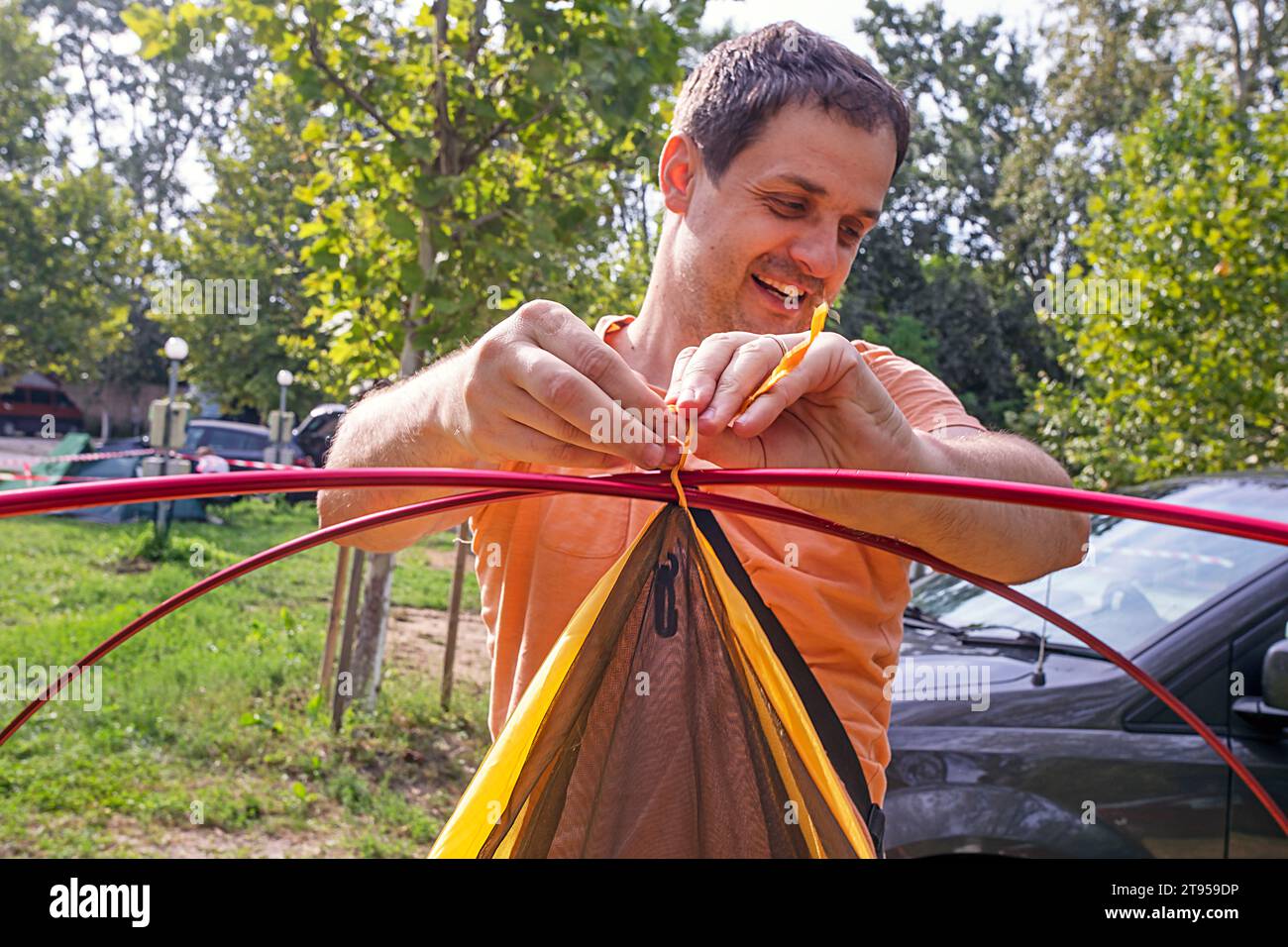 homme heureux installant une tente dans un camp de camping. Vacances en famille et voyages en voiture Banque D'Images
