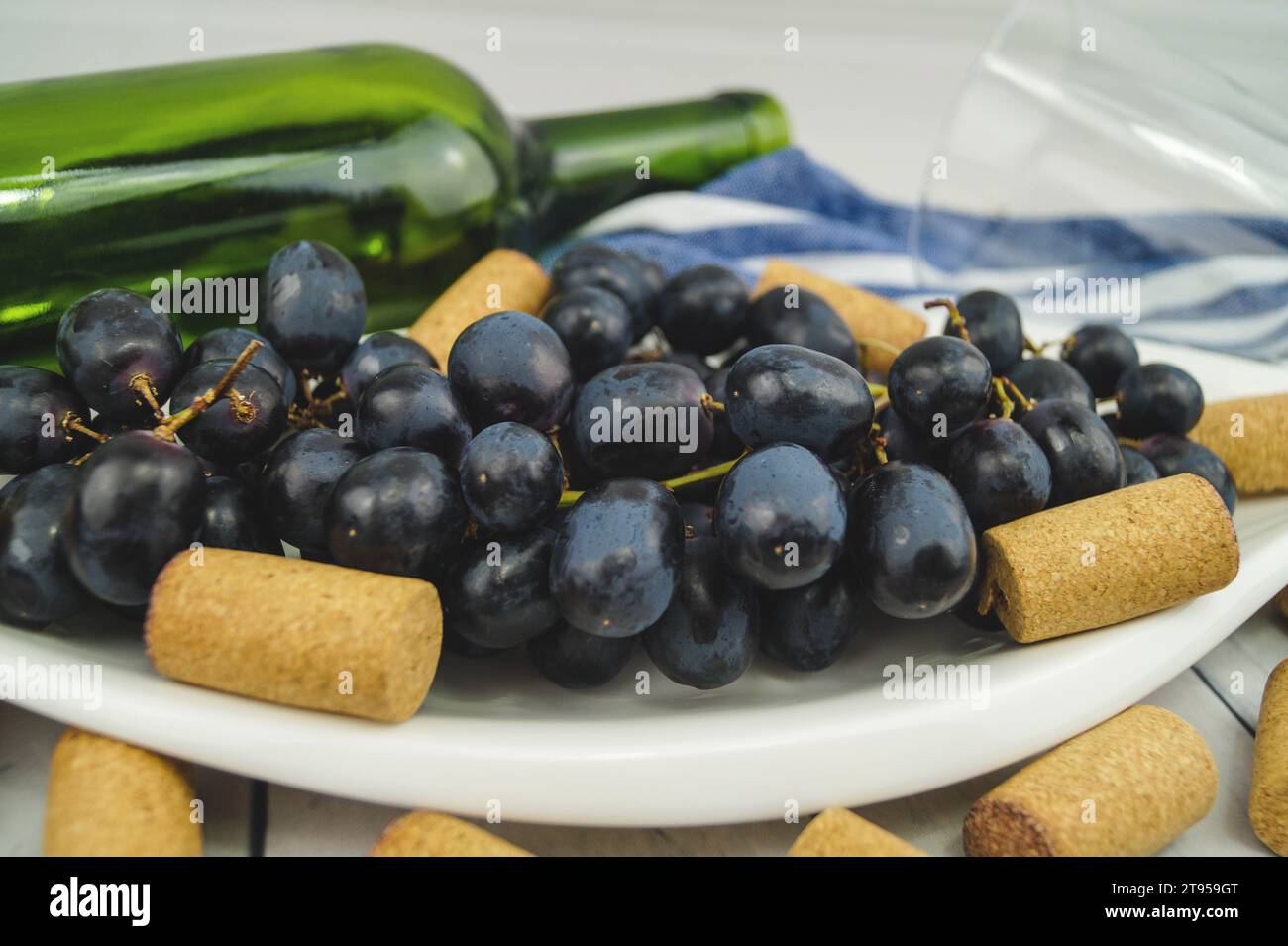 raisins noirs sur assiette, bouchons et bouteille Banque D'Images