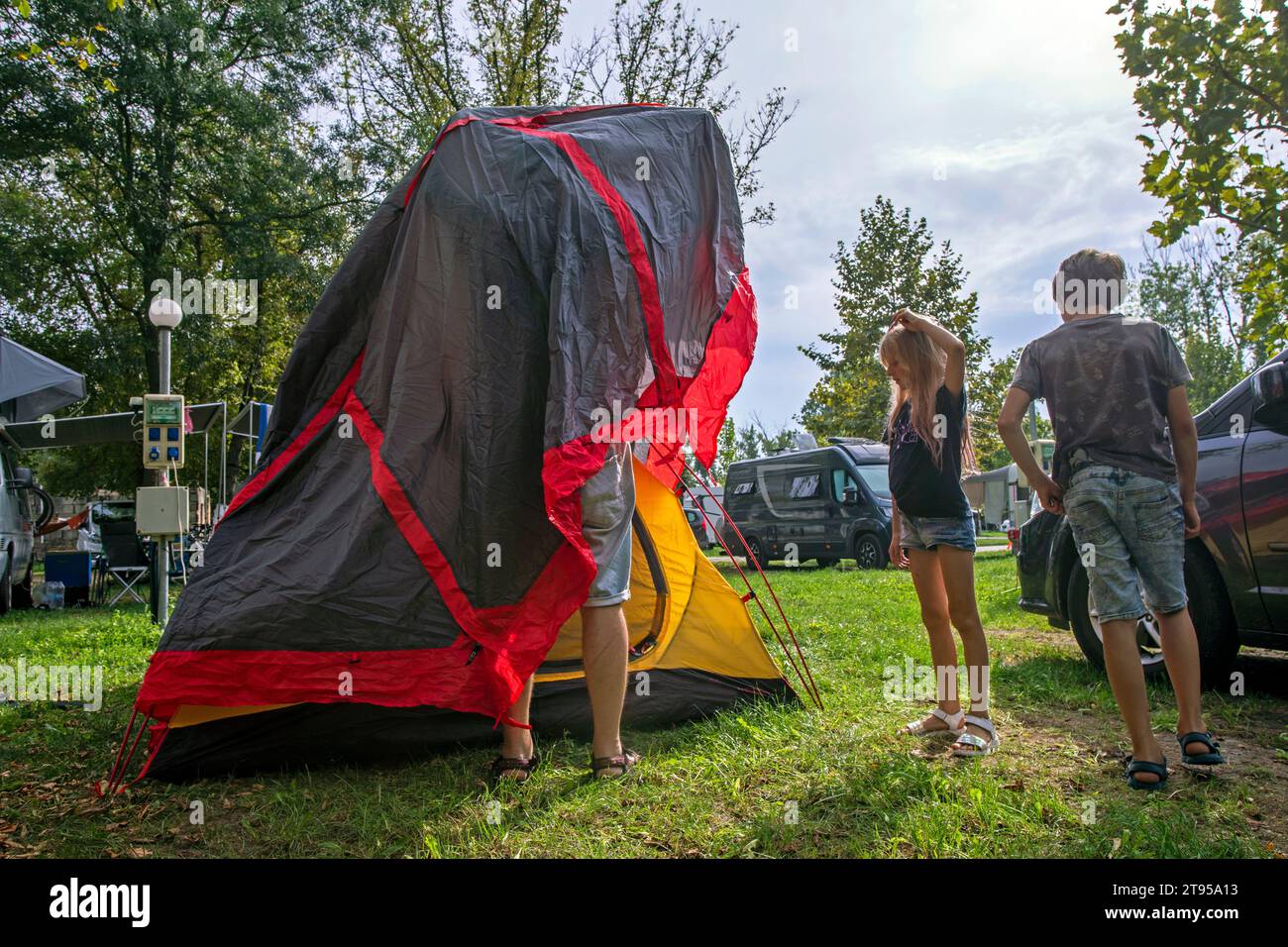 Papa et les enfants couvrent une tente avec un auvent dans un camp de camping. Vacances en famille et voyages en voiture Banque D'Images